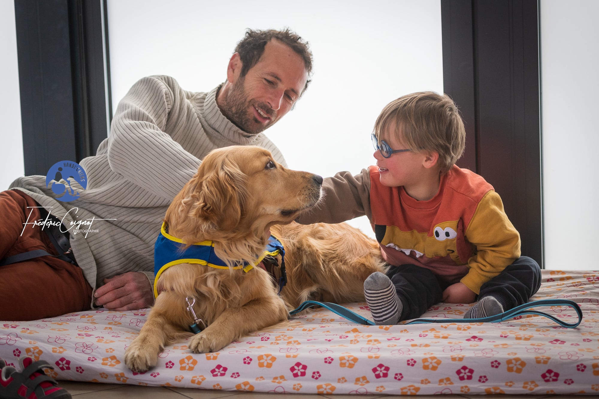 Un petit garçon regarde tendrement son chien d'éveil HANDI'CHIENS