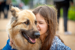 Eleaonor, présentant des troubles du spectre de l'autisme, fait un câlin à Pastel son chien d'assistance formé par HANDI'CHIENS